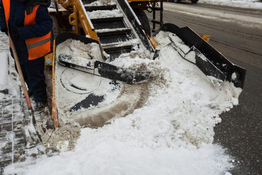 Snow-removal machine cleans the street of snow. Workers sweep snow from road in winter, Cleaning road from snow storm.