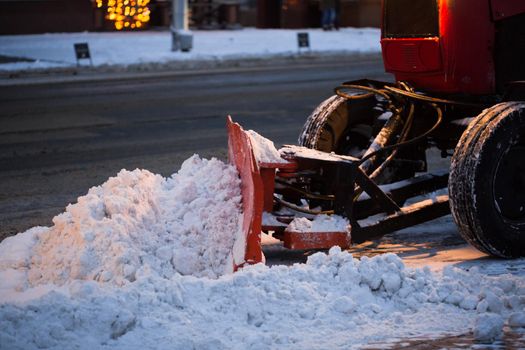 Tractor cleaning the road from the snow. Excavator cleans the streets of large amounts of snow in city.