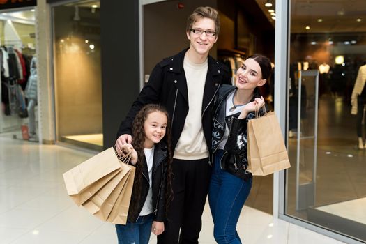 Happy young family with paper bags shopping at the Mall. Shop Windows with clothes