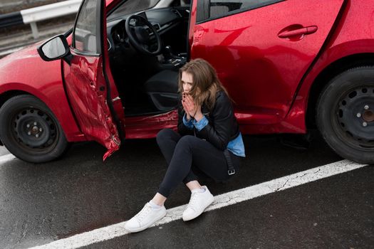 Woman sitting on the road after an accident. Injured woman feeling bad after having a car crash