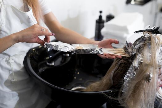 Stylist washes his head in a beauty salon. Hair color dying, foil
