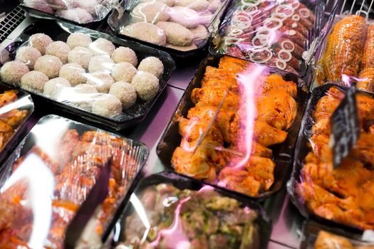 Meats in marinade on supermarket display, pre-cooked food