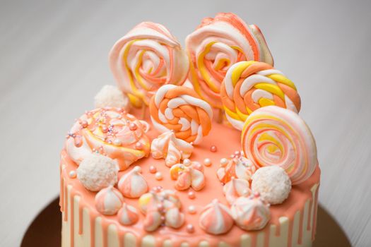 Peach colored cake with meringue, candy, chocolate stains and jelly beans.