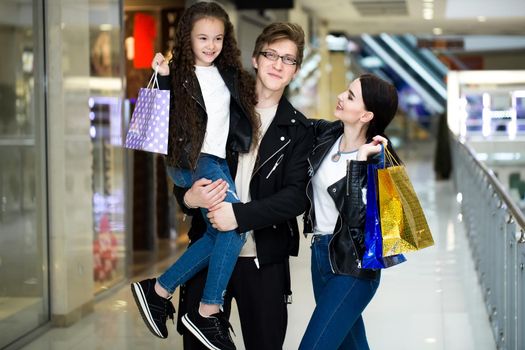 Happy young family with paper bags shopping at the Mall. Shop Windows with clothes