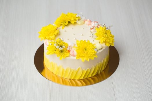 Cake with yellow stains, yellow chrysanthemums and meringue