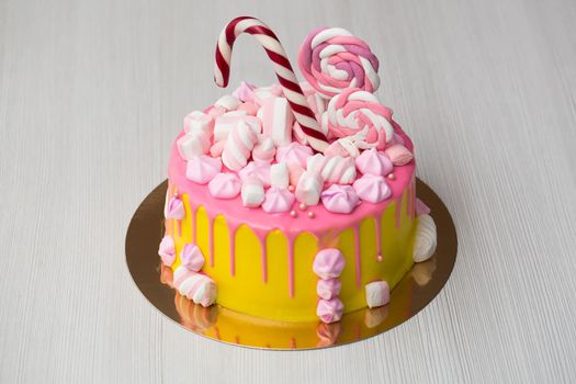 Children's yellow cake with pink frosting, meringue and candies