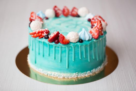 Cake turquoise and blue with strawberries, meringue and candies