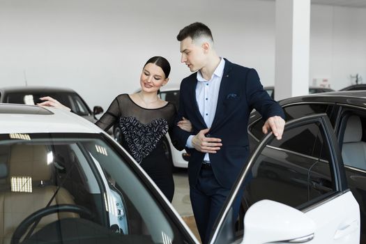 A couple husband and wife choose a car to buy at a car dealership