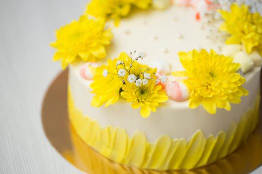 Cake with yellow stains, yellow chrysanthemums and meringue