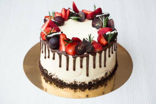 Cake with chocolate stains, strawberries, grapes rosemary