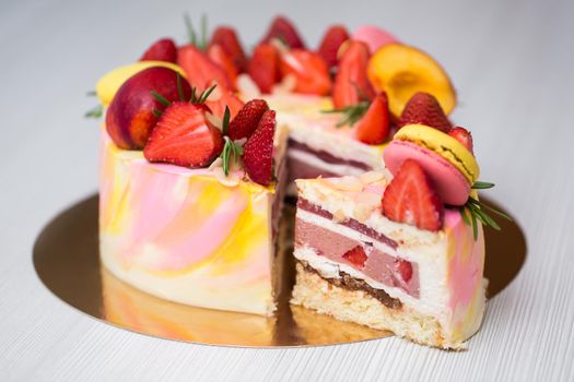 Cake yellow and pink splotches, strawberries, peaches, macaroons, rosemary. The cut of the cake. A piece of cake