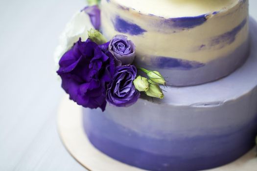 Wedding two-tiered purple cake with fresh flowers.