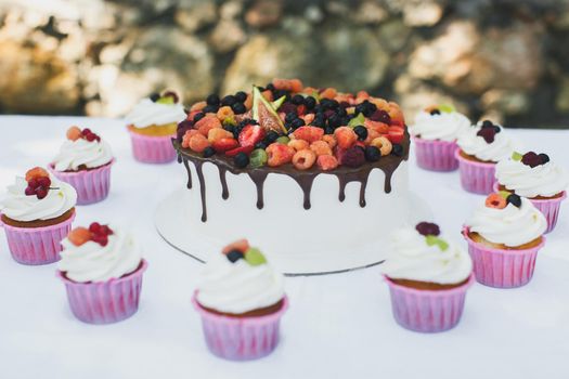 Delicious fruit cake with cupcakes for a happy birthday