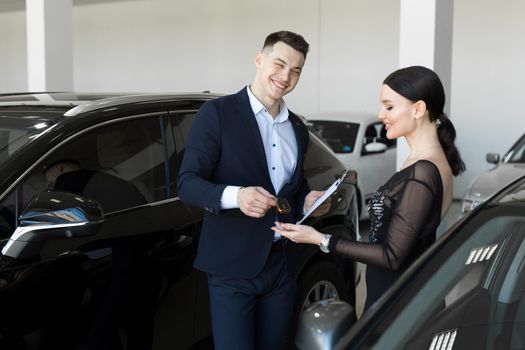 Seller gives the buyer the keys to a new car in the showroom