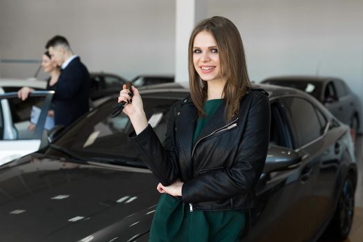 Beautiful woman or car salesman stand holding a new car remote key in a car showroom