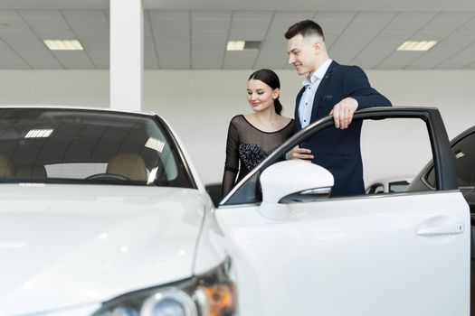 A couple husband and wife choose a car to buy at a car dealership