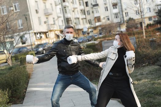 Woman and a man in a coronavirus face mask hold large rolls of toilet paper on a city street and indulge