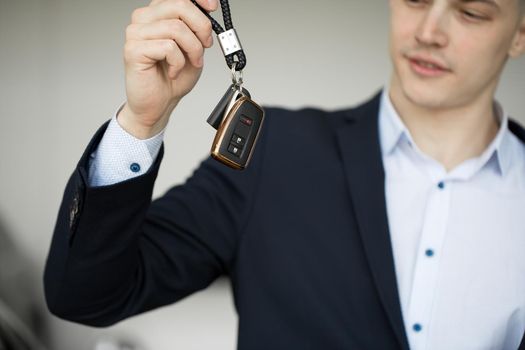 A car dealer with a key in a car dealership close-up