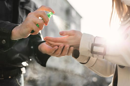 Antiseptic for hands. Fighting viral diseases for prevention. A man applies an antiseptic hand spray to a woman's hands in the fight against the covid 19 coronavirus.