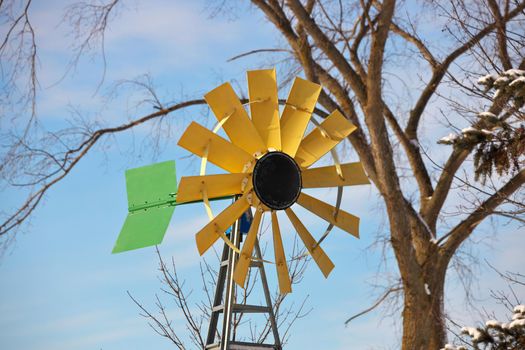 A small Windmill or Wind Turbine in a Rural Setting. Windmill has sunflower colors of yellow brown and green. High quality photo