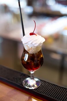 Cocktail with Coca-Cola, ice, ice cream and whipped cream close-up.