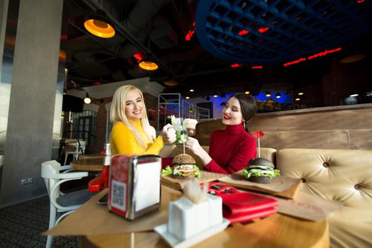 Young women toasting cocktail glasses in a cafe