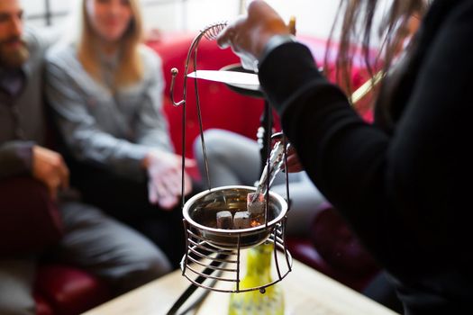 The girl puts hot coals in the hookah with tongs.