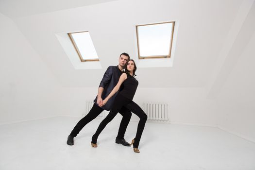 beautiful couple dancing bachata on white background in studio