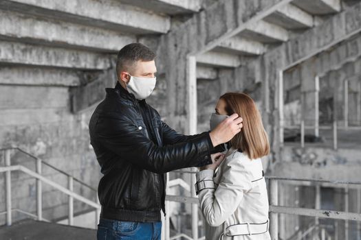 Man puts a protective mask on a woman's face. Coronavirus, Covid-19.