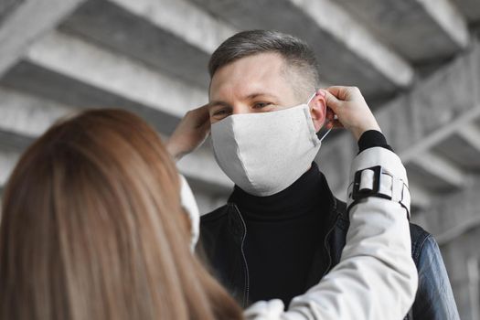 Woman puts a protective mask on a man's face. Coronavirus, covid19.