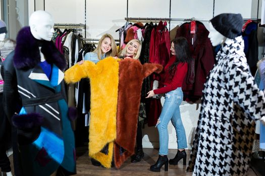 Three women trying on a fur coat in the store