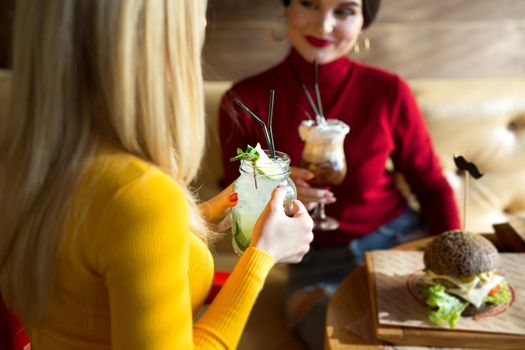 Young women toasting cocktail glasses in a cafe