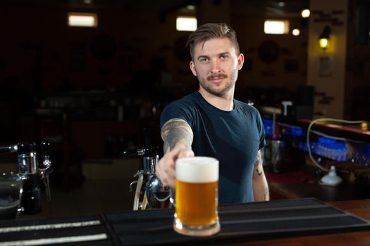 Close up of handsome barman holding a pint of beer in a pub