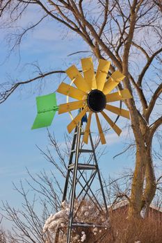 A small Windmill or Wind Turbine in a Rural Setting. Windmill has sunflower colors of yellow brown and green. High quality photo