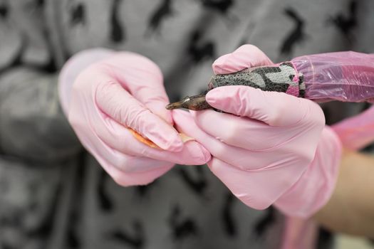 Close-up of the face of a tattooist girl with light hair, who is holding a tattoo machine in her hand. Portrait of a tattoo artist while working in a tattoo parlor.