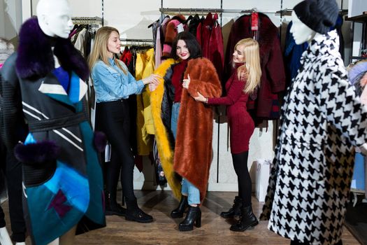 Three women trying on a fur coat in the store