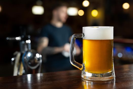 Glass of light beer on a dark pub