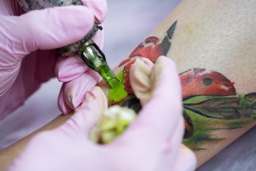 Close-up of a female artist making a color tattoo on the leg of a young girl. Tattoo artist stuffs a ladybug on a girl's leg, tattoo for a girl