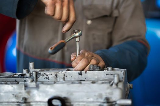 An auto mechanic repairs an internal combustion engine.