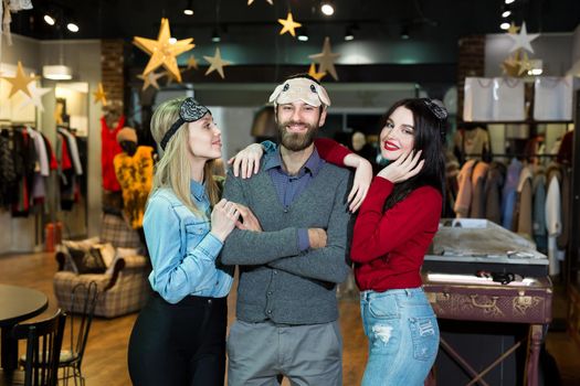 Portrait of beautiful two women and a man in a sleeping mask in a clothing store