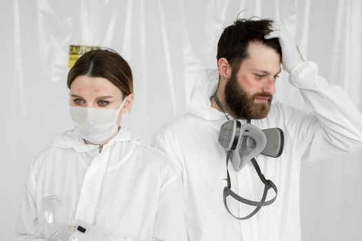 Exhausted doctors or nurses taking of protective mask uniform. Coronavirus Covid-19 outbrek. Mental state of medical professional. Overworked health workers with tears in his eyes.