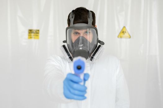 Doctor wearing protective mask ready to use infrared forehead thermometer to check body temperature for virus symptoms - epidemic virus outbreak concept. Coronavirus.Thermometer gun.