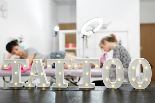 Close-up of the interior of a modern tattoo salon, on the shelf is the word-tattoo