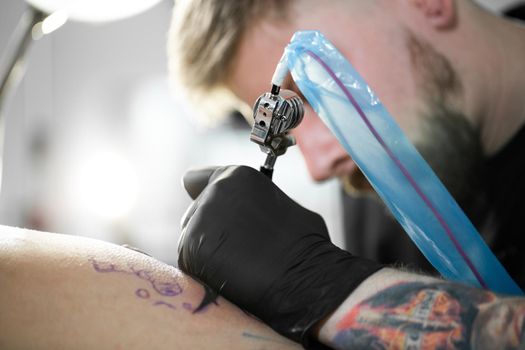 Close-up of tattooist draws on girl's hip