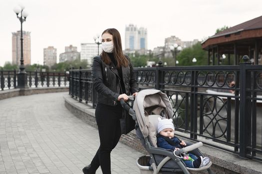 Woman with face mask for protection from coronavirus, covid-19 push a stroller in the street