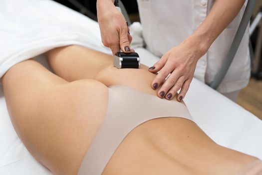 Sexy young girl is lying on the couch in a cosmetology clinic and she is given a vacuum massage with a special medical device. Hardware cosmetology. Body care