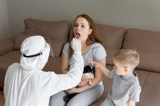 Doctor in personal protective equipment or ppe doing nasopharyngeal swab to patient with covid-19 or coronavirus infection to confirm diagnosis in the isolation unit