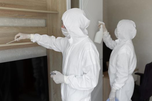 Virologists, people in protective suits carry out the disinfection in the apartment. Wipe furniture and take samples for contamination from the surface during a coronavirus epidemic. Covid - 19.