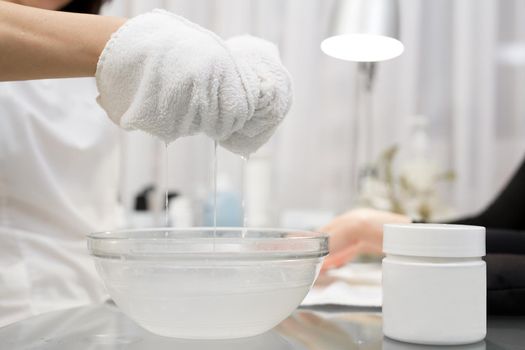 Beautician makes spa treatments for the care hands of a young girl in the beauty parlor. A manicurist wipes her hands with a wet towel to a client after scrub and massage