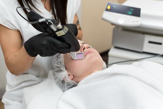 Hair removal cosmetology procedure from a therapist at cosmetic beauty spa clinic. Laser epilation and cosmetology